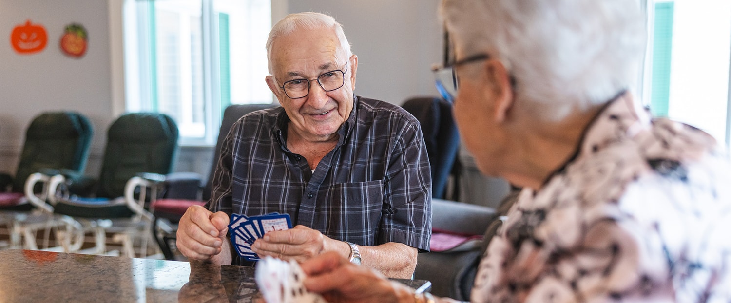 Couple de personnes agées jouant aux cartes avec le sourire