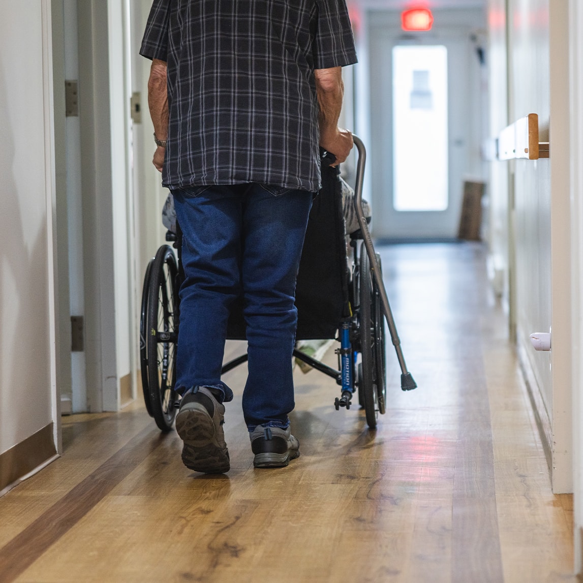 Homme poussant le fauteuil roulant d'une personne à mobilité réduite
